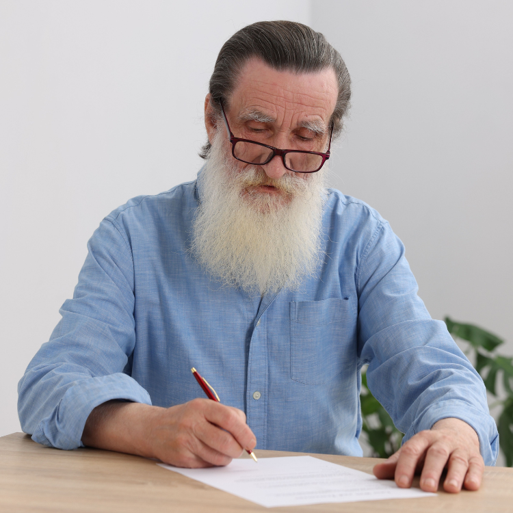 Älterer Mann schreibt konzentriert an einem Dokument zur privaten Vorsorge und Altersabsicherung.